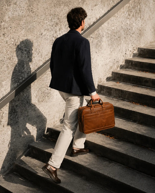 Professional man walking up steps carrying brown leather briefcase, business commuter style, elegant office accessory