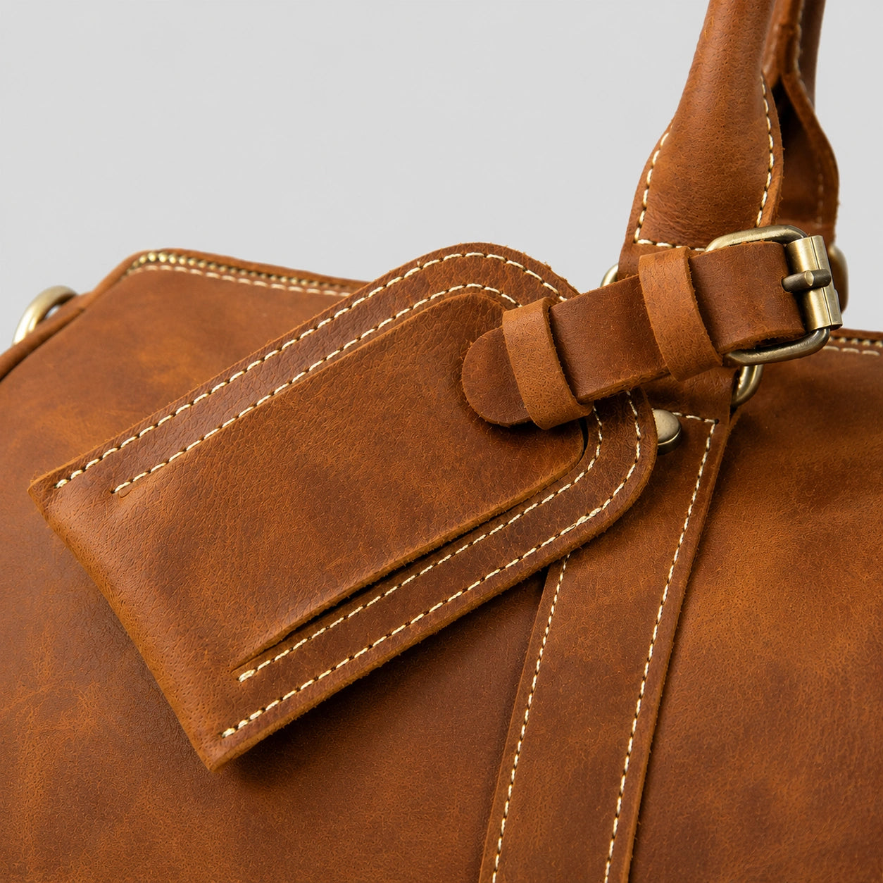 Handcrafted leather luggage tag detail on vintage duffel bag