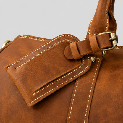 Handcrafted leather luggage tag detail on vintage duffel bag